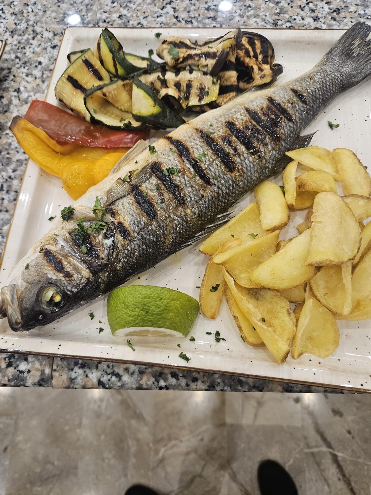 Grilled whole sea bass with potatoes and vegetables